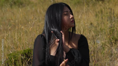 Young latin woman touching her long hair in a field