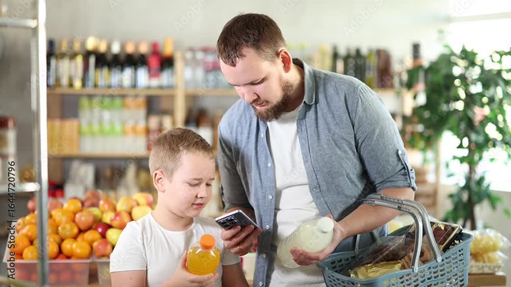 Father and son boy in store scans QR code on carbonated beverage bottle. With help of mobile app, buyers receive information about product. They checks product in registry database of national agency Father and son boy in store scans QR code on carbonated beverage bottle. With help of mobile app, buyers receive information about product. They checks product in registry database of national agency