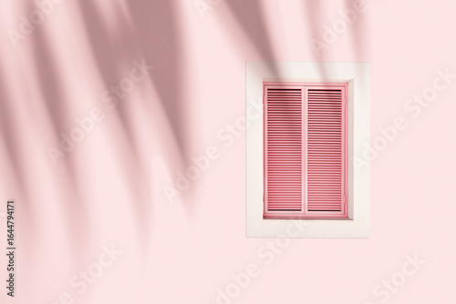 Retro Window with pink closed Shutters Jalousie on pastel pink background with palm leaf shadow, Window frame wood on outdoor wall building. Minimal design abstract. Summer, travel concept copyspace