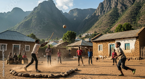 Children playing a lively bat-and-ball game in a dusty rural village at the base of large mountains.