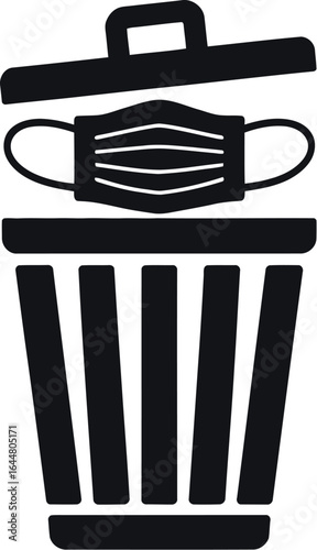 Discarding a medical face mask into a trash can symbolizing end of pandemic