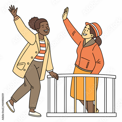 Two happy women of different ethnicities waving hello from a balcony dressed in warm autumn clothing enjoying a friendly greeting