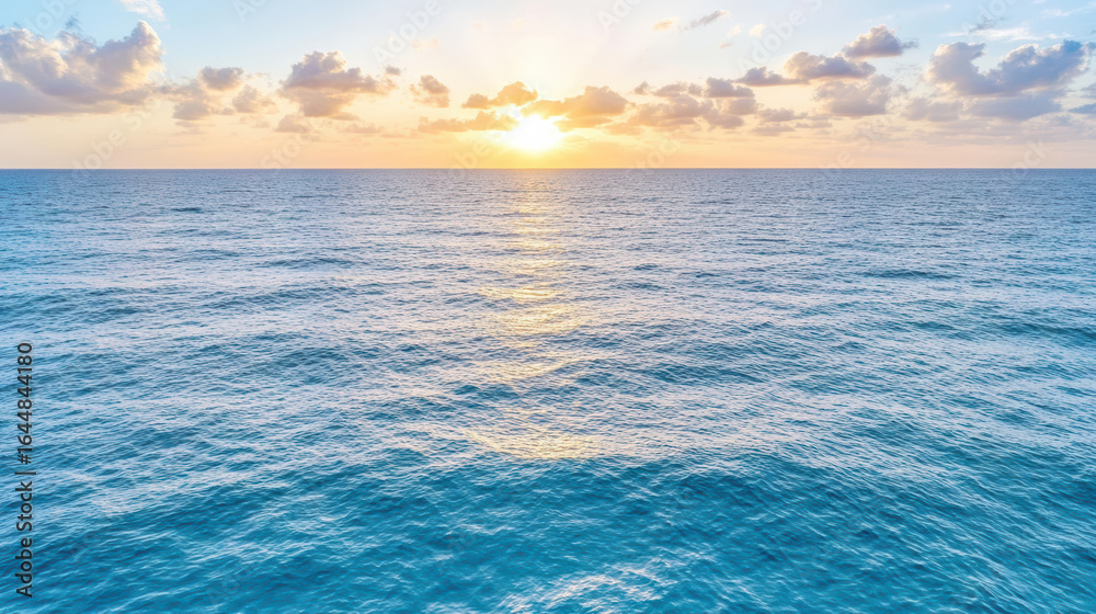 Obraz premium Serene ocean waves reflecting sunlight with soft clouds in sky at sunset