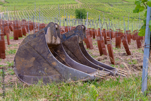 Gros plan sur des godets en réserve : les équipements de terrassement en attente aux abords d'un chantier viticole