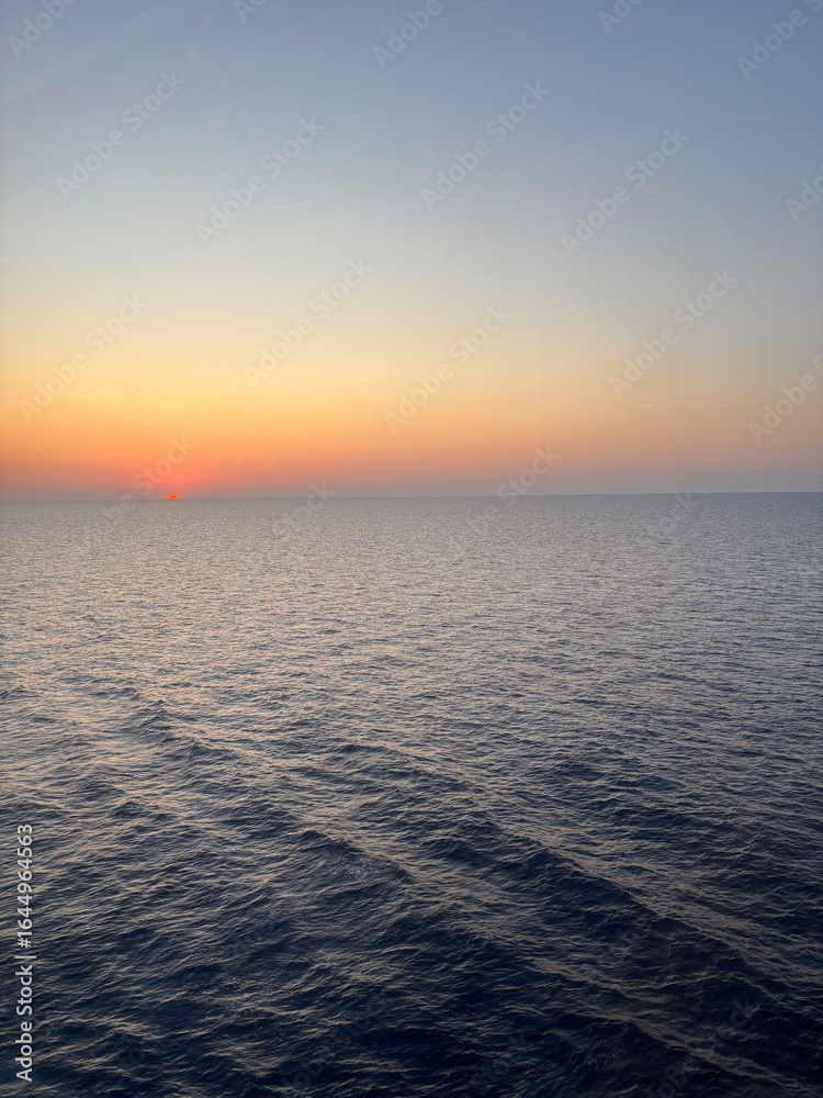 Obraz premium Breathtaking sunset over the sea photographed from the deck of a cruise ship. The golden light reflects on the calm ocean waves