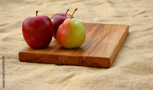 Fruits on a wooden cutting board - two red apples and a pear