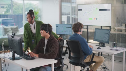 Focused manager provides helpful assistance to customer support representative within modern call center office, creating collaborative team focused on excellent support