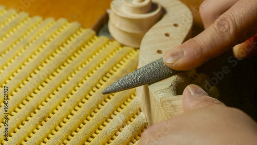 Fotografie Skilled craftsman carefully filing wooden violin component, showcasing meticulou