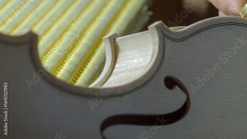 Obraz na plátně Skilled luthier carefully planing wooden surface of violin, refining delicate cu