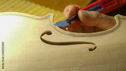 Obraz na plátně Skilled luthier hand carving intricate f hole on violin, revealing delicate craf