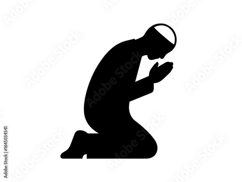Man praying in silhouette with a head covering on knees  