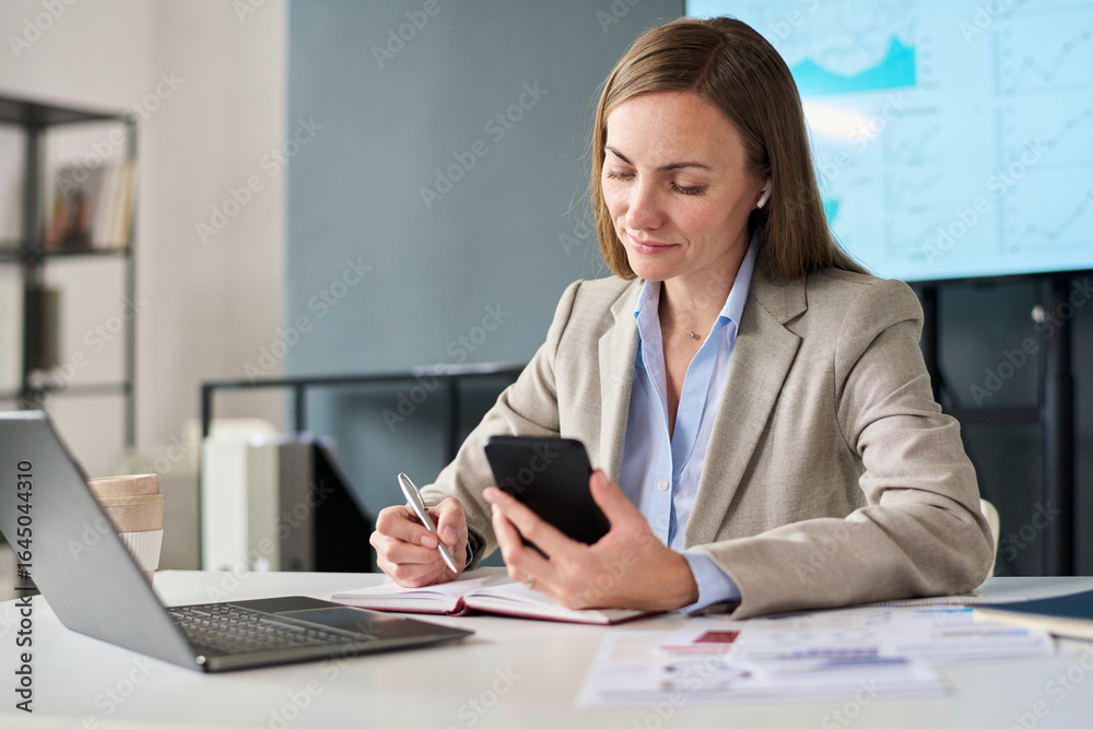 Womanl at desk working with smartphone laptop and financial documents Womanl at desk working with smartphone laptop and financial documents