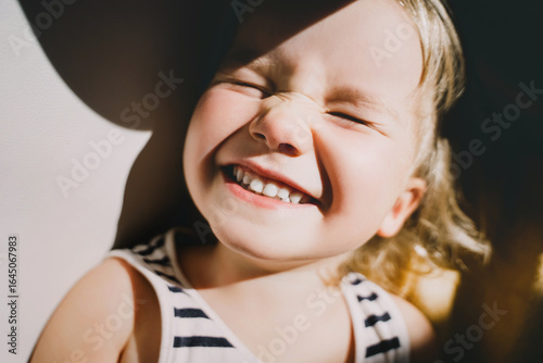 Konstfotografi Cutest little girl smiling and squinting in sunlight