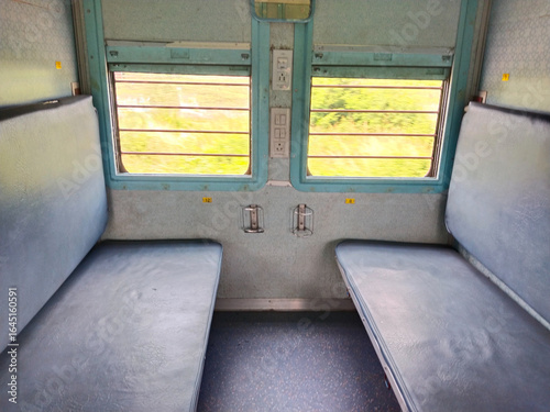 Empty seats, windows and berths inside a second class sleeper compartment in a train run by the Indian Railways. electric sockets for mobile and laptop charging