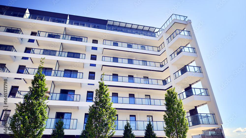 Obraz premium Modern residential building with new apartments in a green residential area. Eco architecture. Green tree and new apartment building. The harmony of nature and modernity.