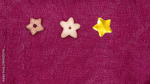 three 5-pointed stars made of different materials on a shiny burgundy background