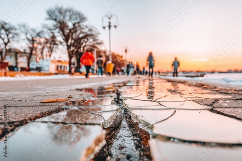 Broken pavement reflecting a winter sunset.  People walking in the background