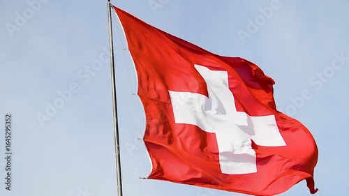 Waving Swiss flag against a clear blue sky during a bright afternoon in Switzerland
