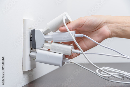 Fotografía Hand inserting electrical plugs into outlet. Electrical overload
