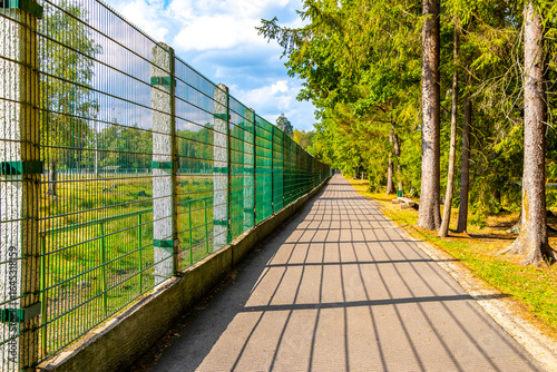 Fotografija Path in the zoo forest by the enclosure fence Belarus.