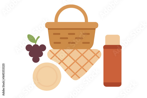Basket with grapes, blanket, and condiment bottle ready for a picnic in a sunny park