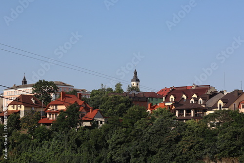 Wallpaper Mural Vibrant hillside village with colorful rooftops and church steeple under clear blue sky Torontodigital.ca