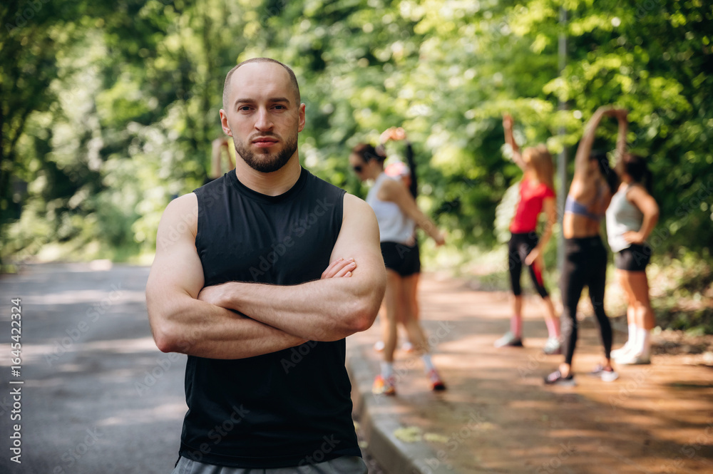 Man is standing in front of people. Group of runners are together outdoors Man is standing in front of people. Group of runners are together outdoors