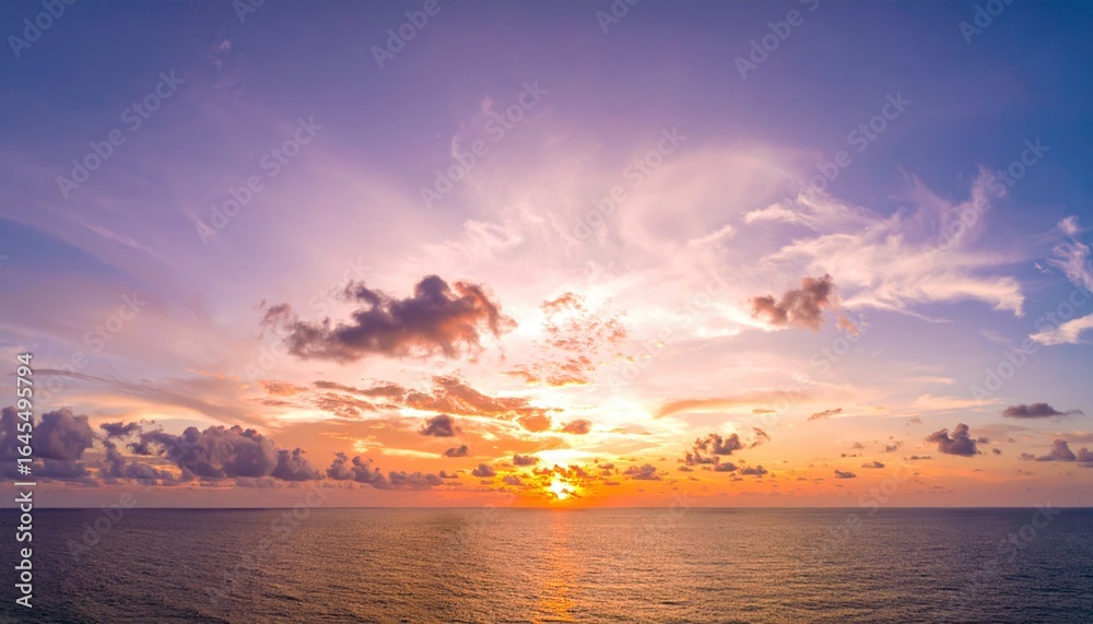 Fototapeta premium Sunset Serenity over the Ocean: A breathtaking panoramic view of the ocean at sunset, with the sky ablaze in vibrant hues of orange, pink, and purple, reflecting on the calm water.