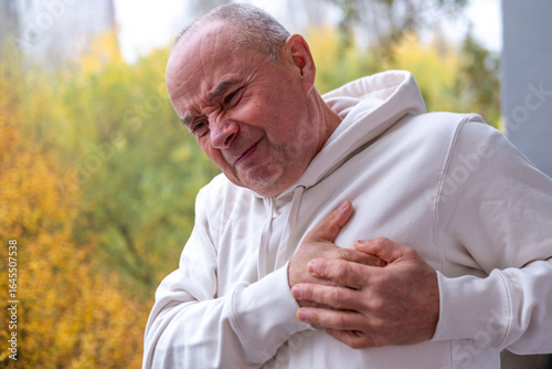Bald man clutching chest in pain, sudden cardiac symptom, heart discomfort, possible rare cardiac condition, health risk, health emergency with worried expression, cardiac arrest