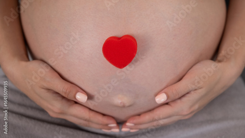 Wallpaper Mural Caucasian pregnant woman holding heart on belly background. Third trimester.  Torontodigital.ca