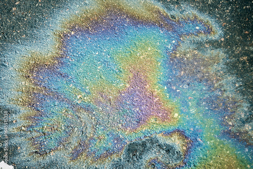Colorful gasoline or oil spill creating a rainbow effect on asphalt, highlighting environmental pollution
