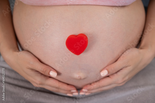 Wallpaper Mural Caucasian pregnant woman holding heart on belly background. Third trimester.  Torontodigital.ca