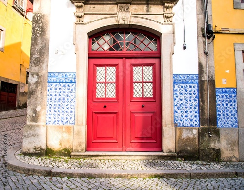 Red door in aged stone building, flanked by blue and white tilework