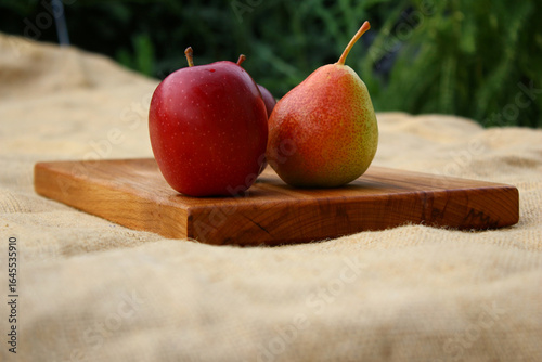 Fruits on a wooden cutting board - two red apples and a pear