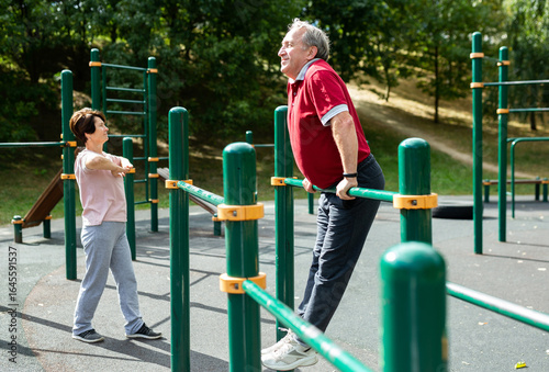  man doing exercises on sports bars in open-air sports area