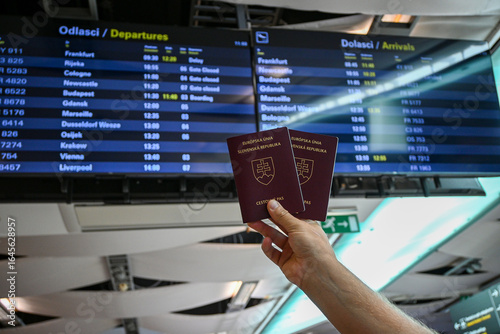 Tableau sur toile Tourist showing slovak passports at the airport, with departures and arrivals bo