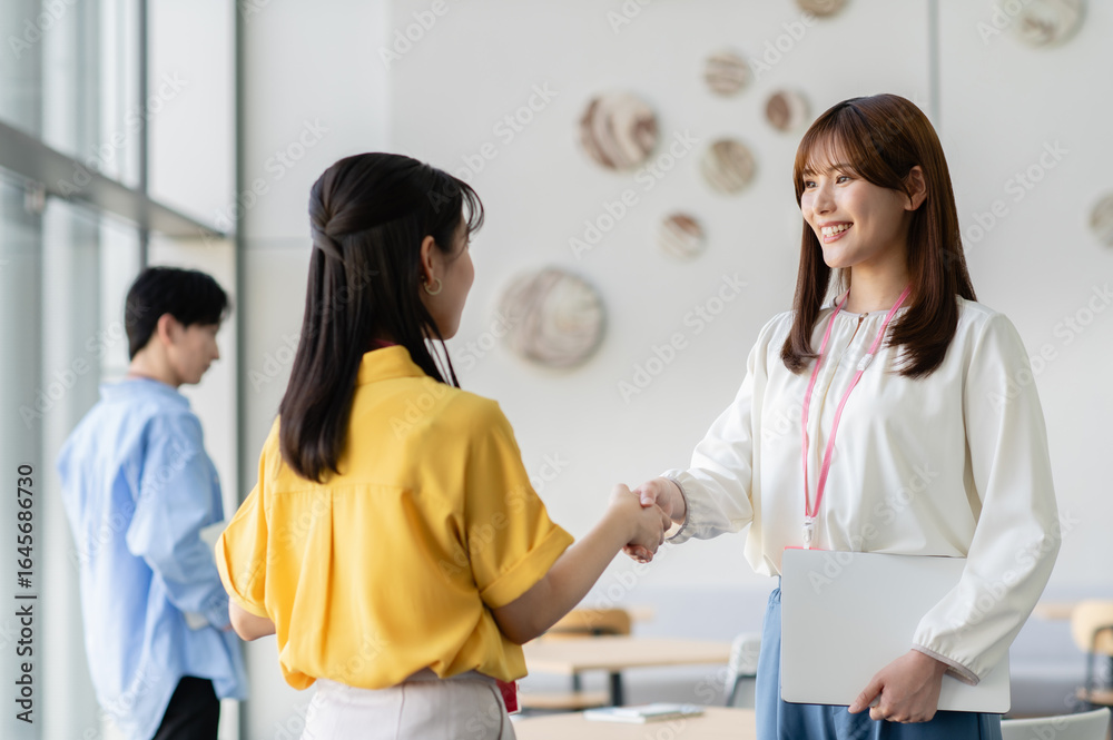 Fototapeta premium 握手する若いビジネスウーマン「撮影協力：スカパー東京メディアセンター」