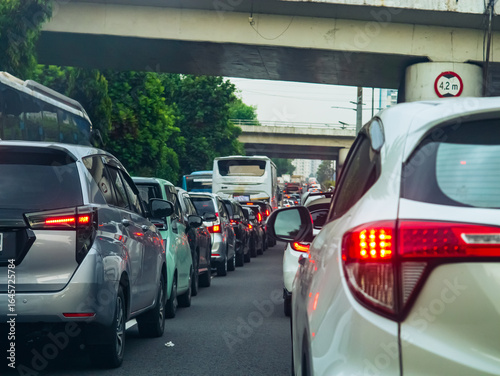 Heavy traffic congestion with rows of cars and buses stuck under a city overpass, highlighting urban transportation challenges and daily commuting issues.