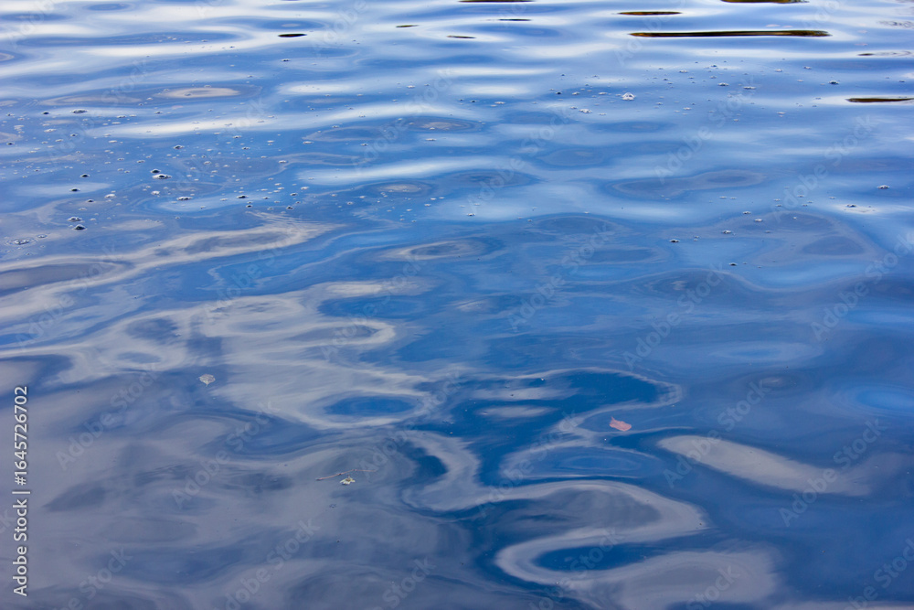 Blue background water surface close-up. A ripple on the water. Blue background water surface close-up. A ripple on the water.