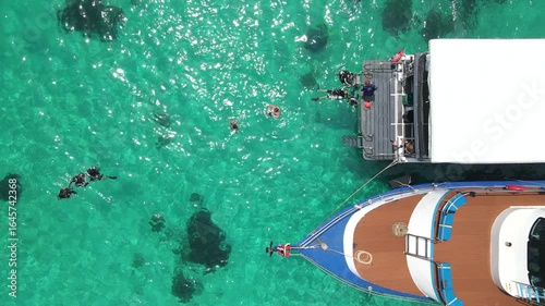 Aerial footage of scuba divers swimming on the surface and climbing up on boat platform at Koh Racha Island, A popular destination for summer activity and scuba diving trip in Phuket, Thailand.