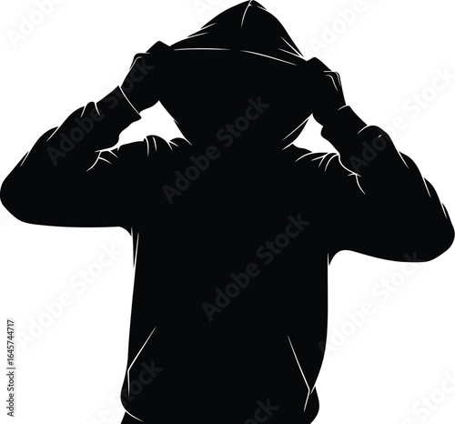 Silhouette of a person wearing a hoodie, creating a sense of mystery and anonymity The dark figure is a man in shadow.