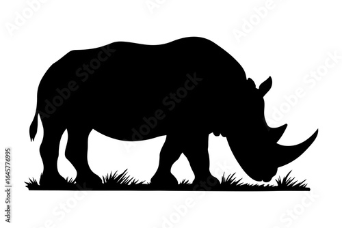 Black silhouette of a rhinoceros grazing on grass