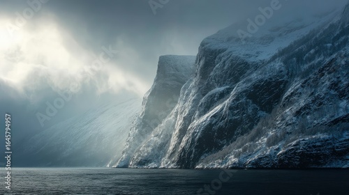 Snow-covered cliffs rising from cold fjord waters, ethereal light breaking through mist