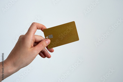 Close-up of a hand presenting a golden credit card on white background, symbolizing premium banking, wealth, and exclusive membership. 