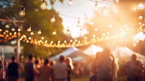 Fototapeta Naklejka Na Ścianę i Meble -  People dancing at a summer festival under string lights in a park
