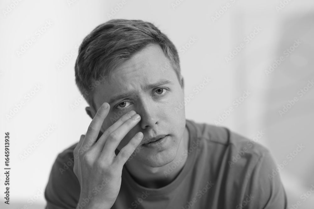 Sad man crying on blurred grey background, black and white effect Sad man crying on blurred grey background, black and white effect