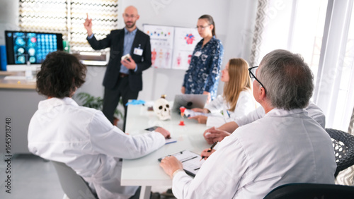 Hospital staff at the presentation of a groundbreaking brain surgery. A group of scientists in white lab coats are sitting at a table