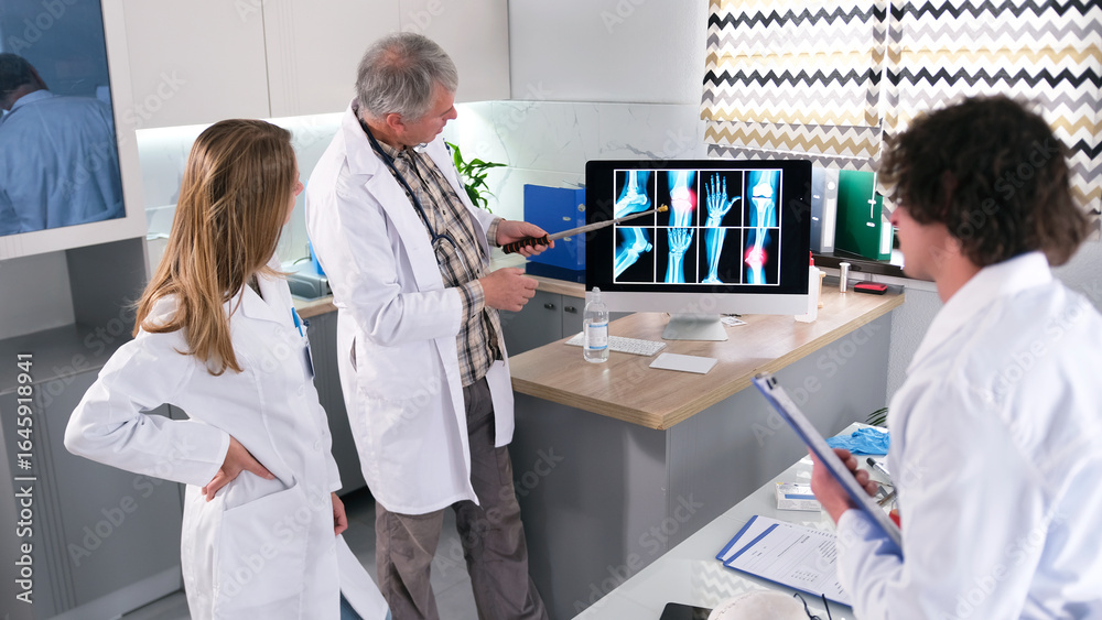 Obraz premium The surgeon discusses the patient's case with the interns. A group of doctors looks at a computer monitor that displays X-rays