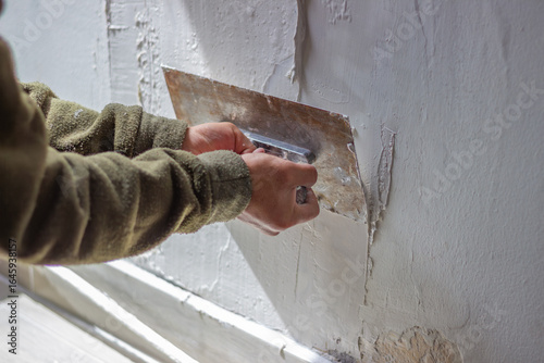 Worker applying plaster on wall with trowel