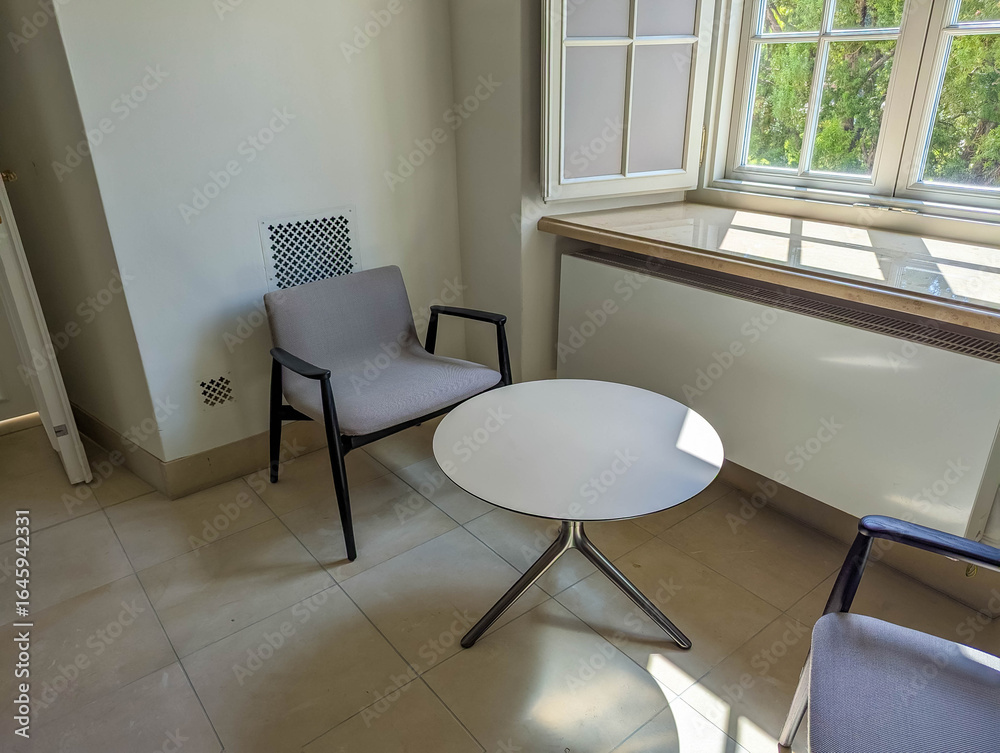 Fototapeta premium Modern office meeting space with round white table and contemporary chairs in well lit interior